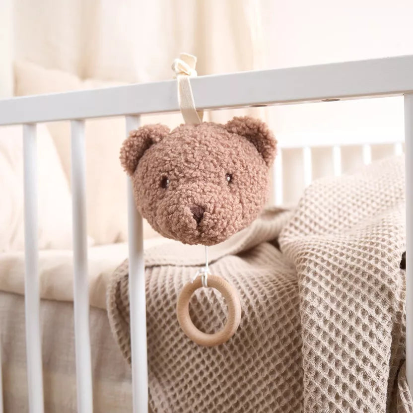 Grojantis meškiukas rudos spalvos, pakabinamas prie vaiko lovytės